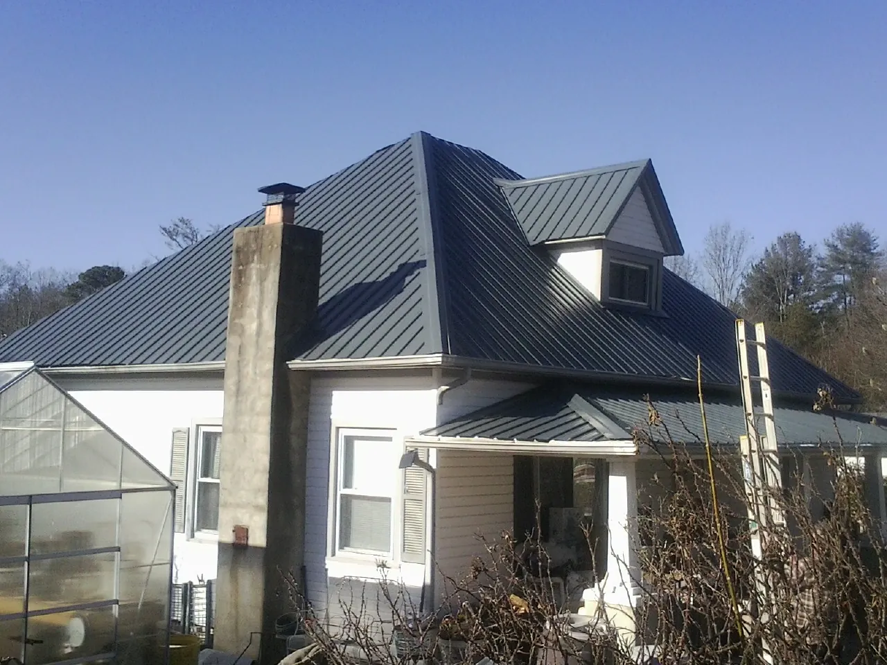 Dark blue standing seam metal roof on a white farmhouse with dormer — Slate & Tile Roof Repair by Roofing Brothers in Loma Linda