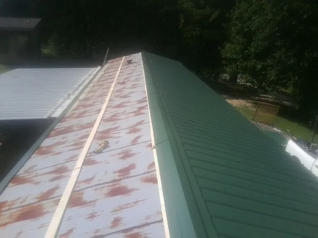 Old rusted panels beside newly installed green metal roofing — Wind Damage Roof Repair by Roofing Brothers in Loma Linda