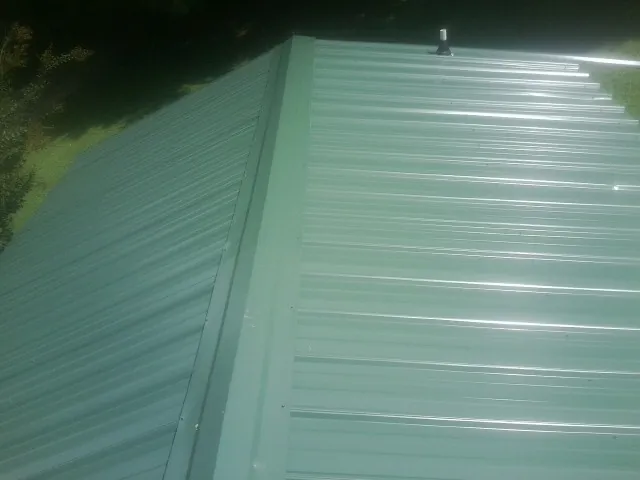 New green metal panels meeting at the ridge of a roof — Flat Roof Repair work by our crew in Loma Linda