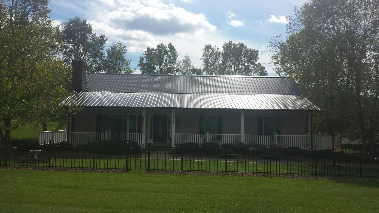 Gray metal roof on a brick ranch with a full width front porch — Gutter Guard Installation work by our crew in Loma Linda