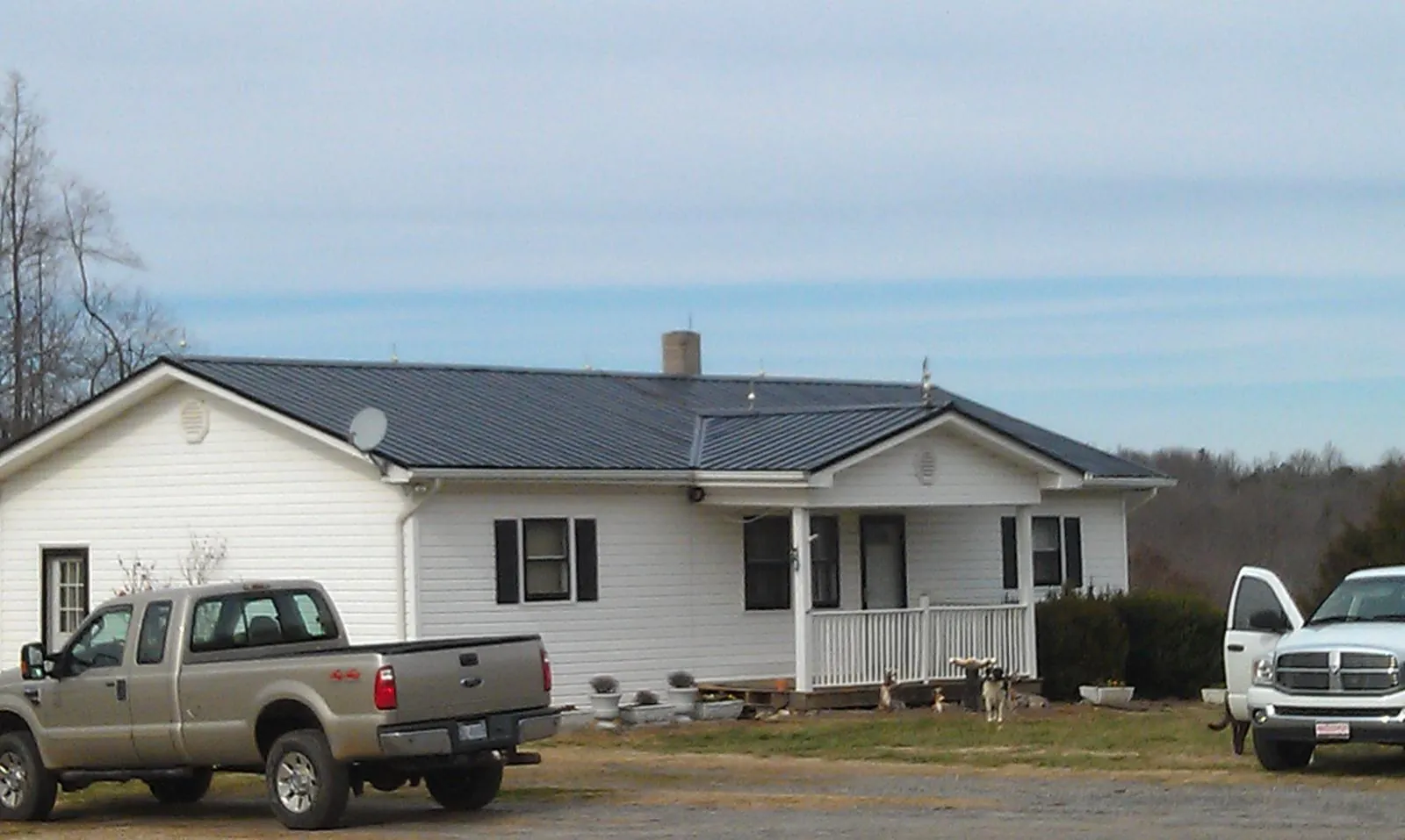 Finished dark metal roof on a white ranch home with work trucks parked in Loma Linda