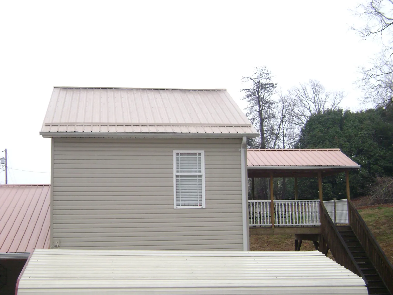 Tan metal roofs on a two story addition and attached porch, from a Roof Replacement job in Loma Linda