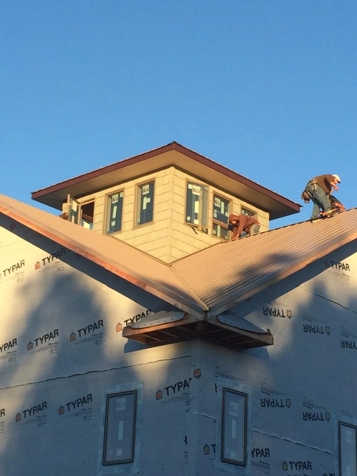 Roofers working around a rooftop cupola on a new metal roof at sunset — Roof Waterproofing in Loma Linda by Roofing Brothers